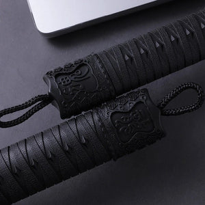 Close-up of two katana umbrella handles with black braided cords