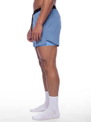 Side view of the Haze Blue 2-in-1 shorts on a model, split outer hem over the fitted inner layer