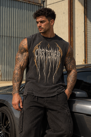 A tattooed model leans on a grey car in the washed black muscle shirt, worn with black cargo jeans