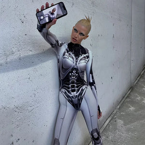 Person in a futuristic, form-fitting suit taking a selfie against a plain wall.