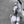 Person in a futuristic, sci-fi costume with white hair and pointed ears against a gray wall.
