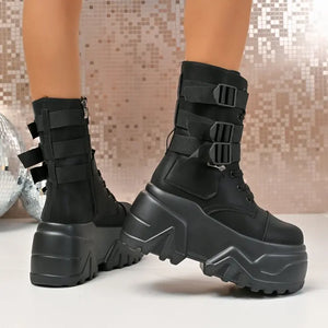Black platform boots with buckle details on a neutral background