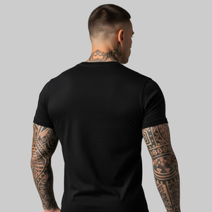 Man wearing a black t-shirt with visible tattoos on arms and neck against a gray background