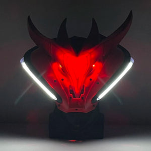 Dragon head mask with red glowing eyes and white accents on a dark background