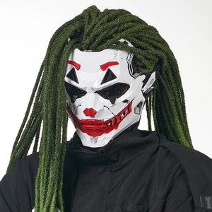 Person wearing a white mask with red and black accents, green dreadlocks, and a black outfit on a white background
