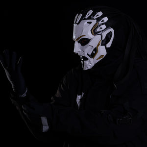 Person wearing a detailed mask with white and black design, against a dark background