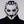 Person wearing a white and black mask with gold accents on a gray background