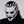Person wearing a white and black mask with gold accents on a gray background