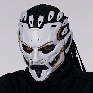 Person wearing a white and black mask with gold accents on a gray background