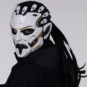 Person wearing a white and black mask with gold accents on a gray background