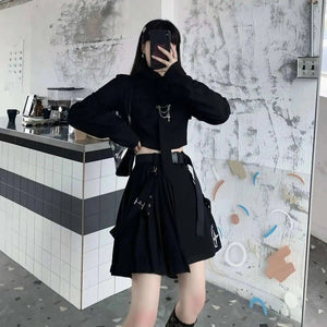Person wearing a black outfit with unique designs in a modern interior setting.