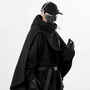 Person wearing a black outfit with a cape and mask on a white background