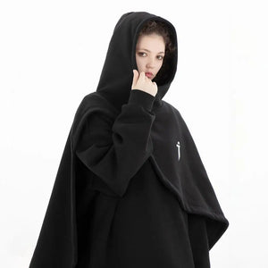 Person wearing a black hooded cloak with a small white logo on a white background