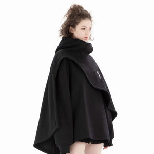 Person wearing a black poncho with a brand logo on a white background