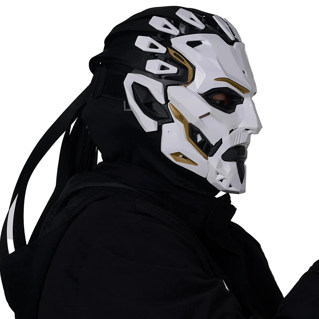 Person wearing a futuristic white and black helmet with gold accents on a plain background