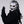 Person wearing a white mask with black and gold details and black gloves on a light gray background