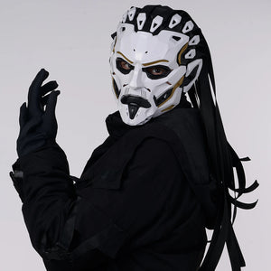 Person wearing a white mask with black and gold details and black gloves on a light gray background