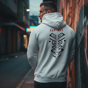 Man wearing a white hoodie with a black geometric design on the back, leaning against a graffiti-covered wall.