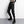 Black strap techwear joggers, front view with a hanging strap, green badge on the cargo pocket and black boots