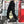 Black snap pocket techwear joggers worn on a city street, side view of the snap-flap cargo pocket and red tab