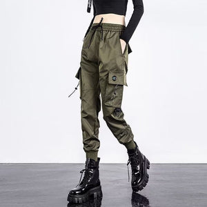 Army green toggle techwear joggers, woman in front view with a drawstring waist, cord toggles and ankle cuffs