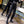 Two women in black label cargo joggers with yellow label patches, front view, tapered legs into black boots