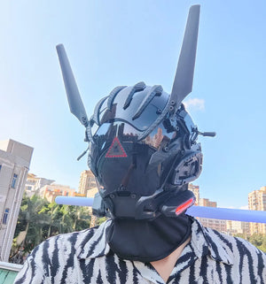 Black techwear mask with tall antenna blades and a red triangle indicator