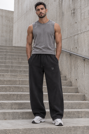 Black baggy barrel leg sweatpants on a man standing on steps, front view with the dark drawstring