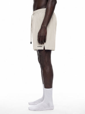 Side view of the Pale Khaki lined shorts on a model, showing the loose leg and the split side hem