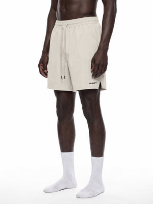 Pale Khaki baggy workout shorts in three-quarter front view on a model, long drawstring hanging loose