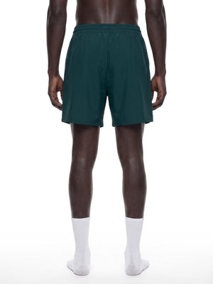 Set bagfra: dybturkise baggy gymshorts på en model, afslappet pasform der slutter over knæet