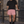 Pink baggy lined gym shorts worn with a black tee by an iron railing, front view of the drawstring waist