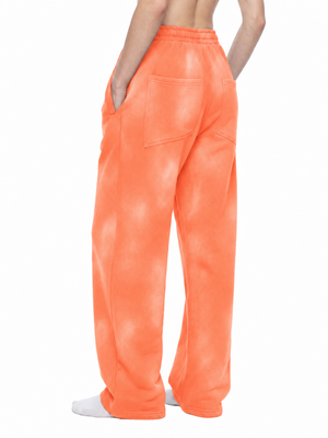 Orange sweatpants in a back three-quarter view, with a back patch pocket and the relaxed wide leg cut