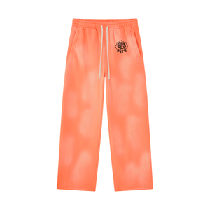 Orange sun faded sweatpants laid flat, front view with white drawstring and black rose near the waistband