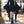 Woman walking in the black Bat Sleeve Goth Dress, front view of the lace-up neckline and pointed wing sleeves