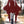 Dark red bat wing mini dress with a lace-up V neck and lace frills at the wrists, front view outdoors