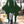 Dark green elf style mini dress with bat wing sleeves and lace-up neckline, front view in a park