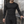 Model in the black compression shirt leaning on a railing in a tiled stairwell, front three-quarter view