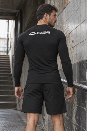 Back view of the black long sleeve compression shirt in a tiled stairwell, white CYBER logo on the upper back