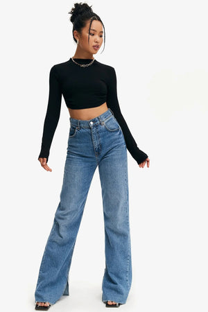 Full length view of the black crop top with wide-leg blue jeans and black heels, long sleeves and mock neck