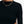 Close-up of the black long sleeve crop top neck and shoulder with a chain necklace, the curved hem at the waist