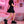 Woman in a short black dress wearing the black thick platform sneakers in a pink neon bedroom