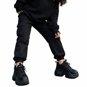 Black platform sneakers worn with black cargo joggers, front view of the thick sole and lace-up upper