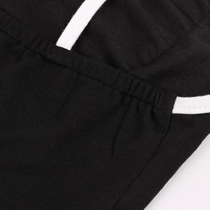 Close-up of the elastic gathered waistband of the black mini skirt with a white piped seam