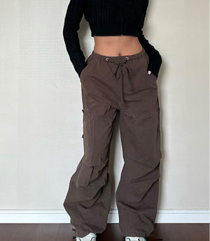 Woman with hands in the pockets of brown wide leg cargo pants, front view with a cropped black cardigan