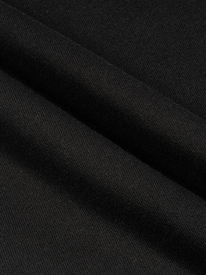 Folds of the black cotton laid across each other, showing the weight and matte surface of the knit