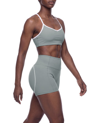Side view of the model walking in haze blue, the short cropped bra sitting high on the ribs