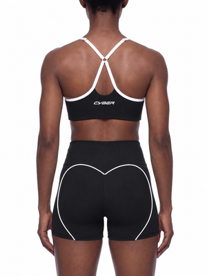 A model seen from behind in the black sports bra, the Y back and the white trim across the band