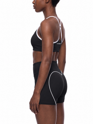 Side view on the model, the black body edged in white and the thin strap running over the shoulder