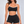 A second model wears the black color block sports bra with black shorts, front view on a grey backdrop